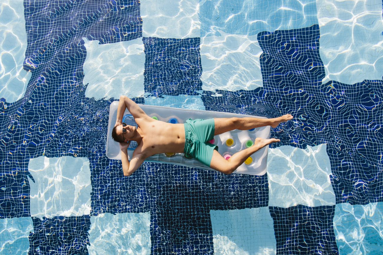 Man Floating in Pool on Vacation Man Floating in Pool on Vacation
