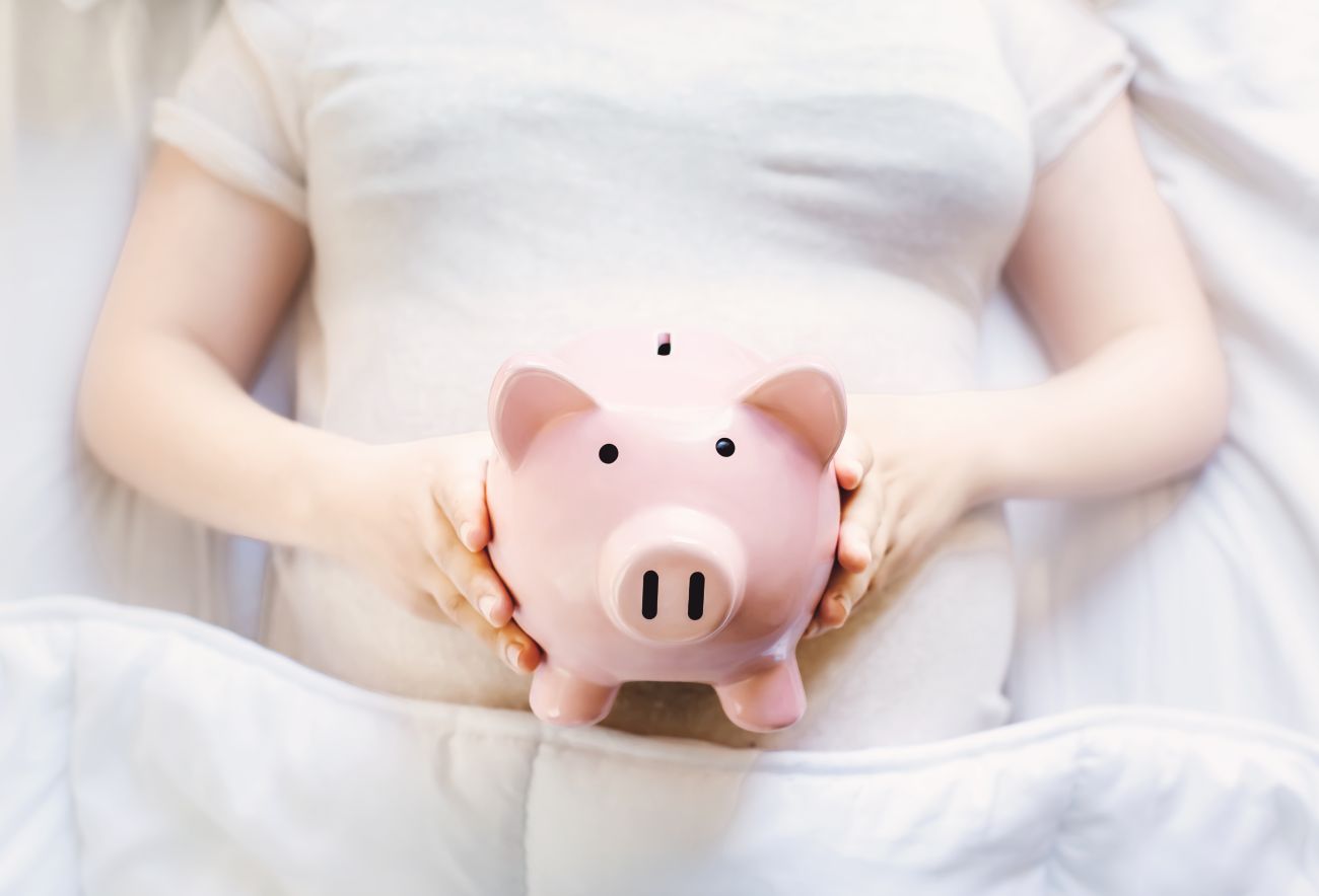 Woman Lying in Bed with Piggy Bank Woman Lying in Bed with Piggy Bank