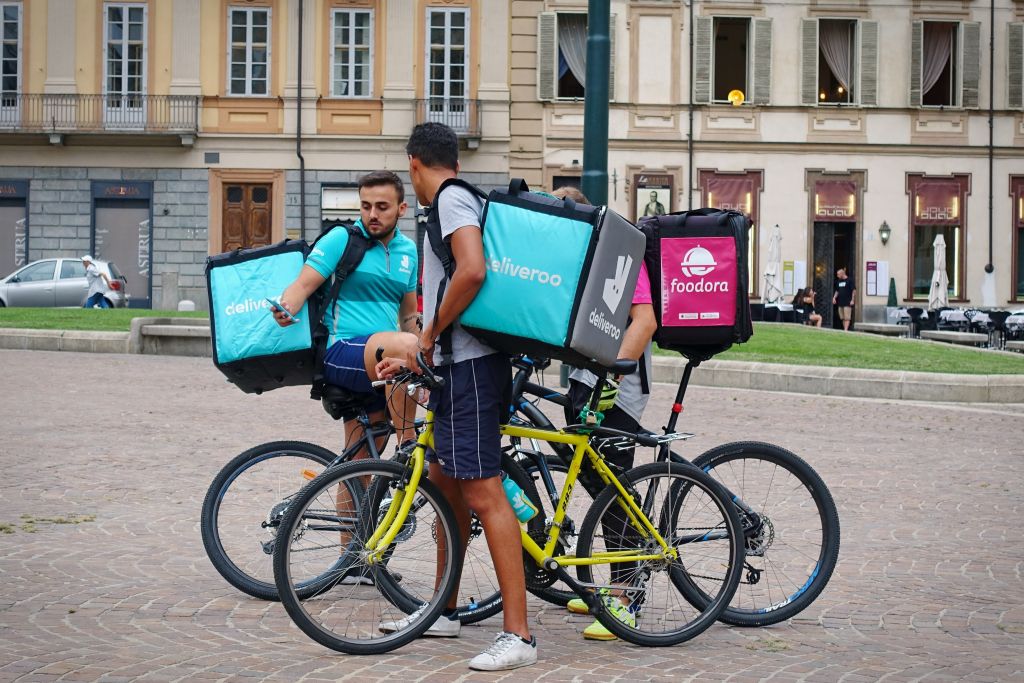 Gig Workers Looking at Phone on Delivery Bike Gig Workers Looking at Phone on Delivery Bike