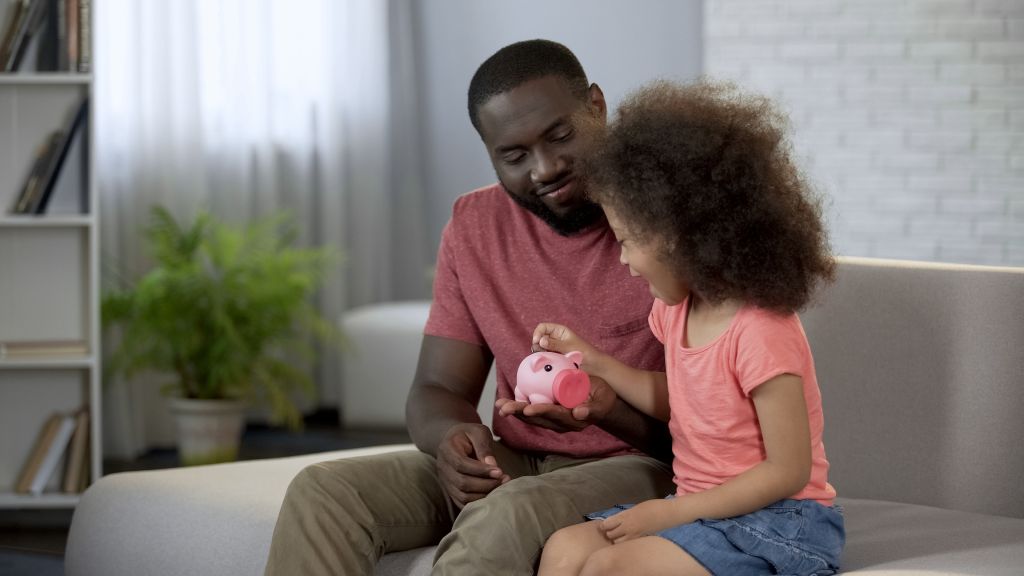 Child Putting Money into Piggy Bank Father is Holding Child Putting Money into Piggy Bank Father is Holding