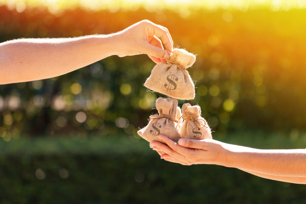 Person Handing Another Person Bags of Money Person Handing Another Person Bags of Money