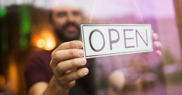 Man Putting Up Open Sign on Business