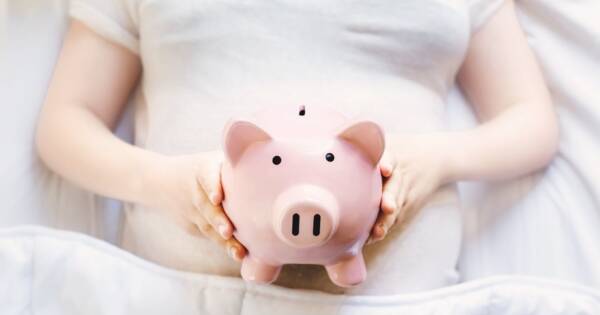 Woman Lying in Bed with Piggy Bank