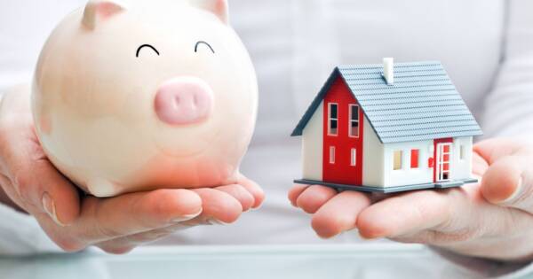 Person Holding a Piggy Bank and Tiny Home