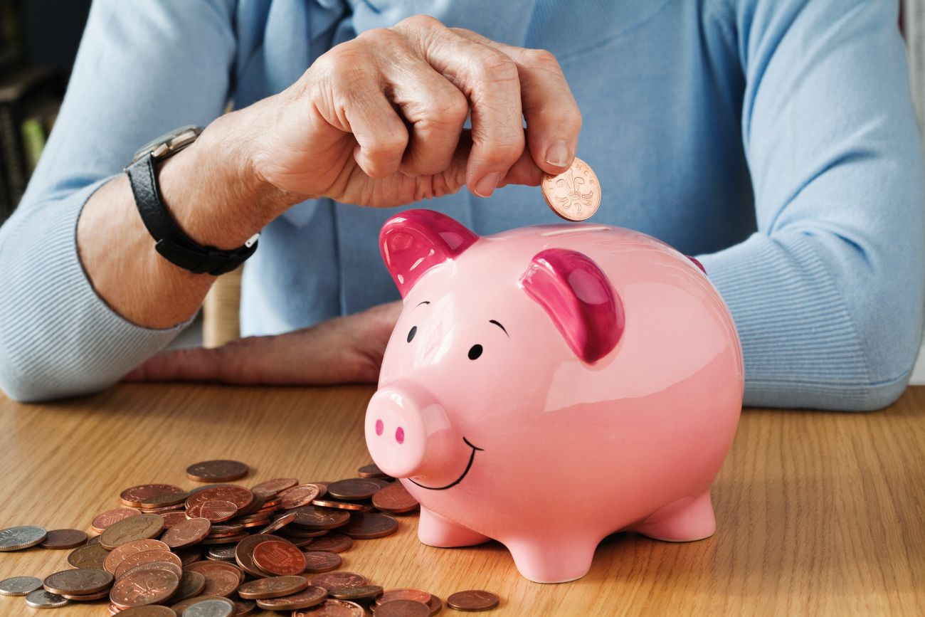 Retired Woman Putting Money in Piggy Bank Retired Woman Putting Money in Piggy Bank