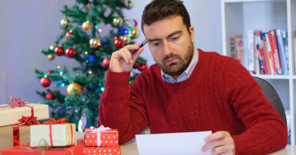 Man Upset Looking at Bills with Christmas Tree