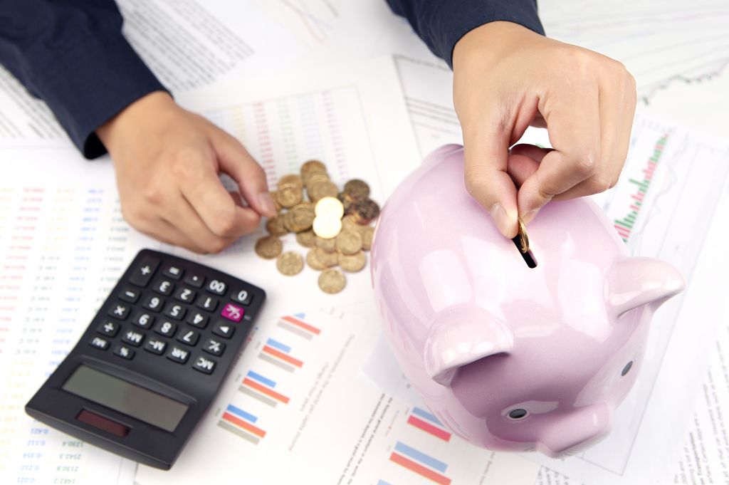 Woman Putting Coins in Piggy Bank Woman Putting Coins in Piggy Bank