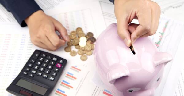 Woman Putting Coins in Piggy Bank