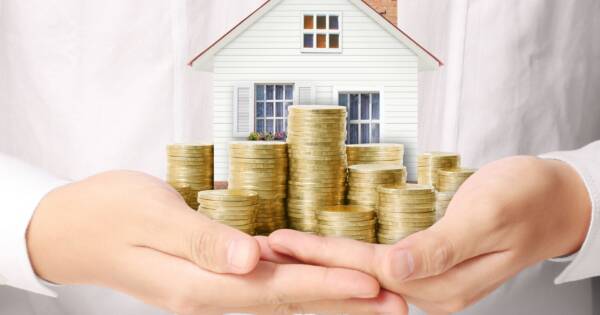 Woman Holding Little House and Gold Coin Stacks