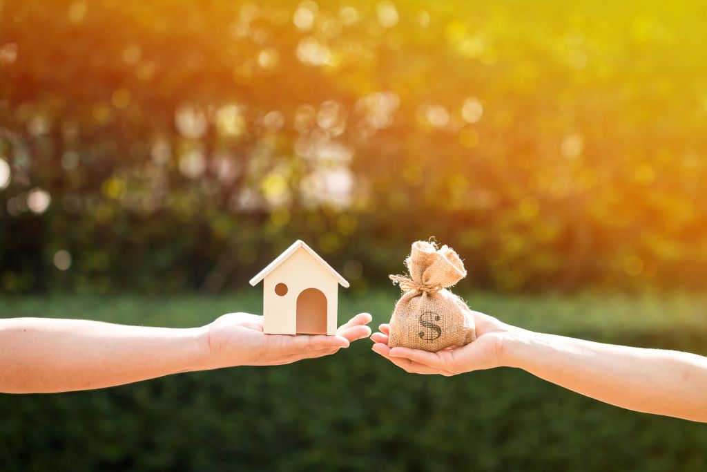 Hands Holding Home and Bag of Money Hands Holding Home and Bag of Money