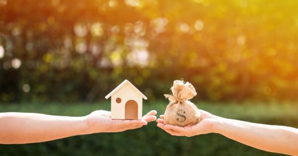 Hands Holding Home and Bag of Money