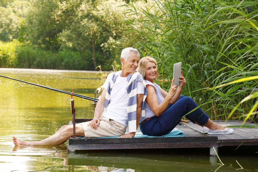Retired Couple Relaxing on Dock with Tablet Retired Couple Relaxing on Dock with Tablet