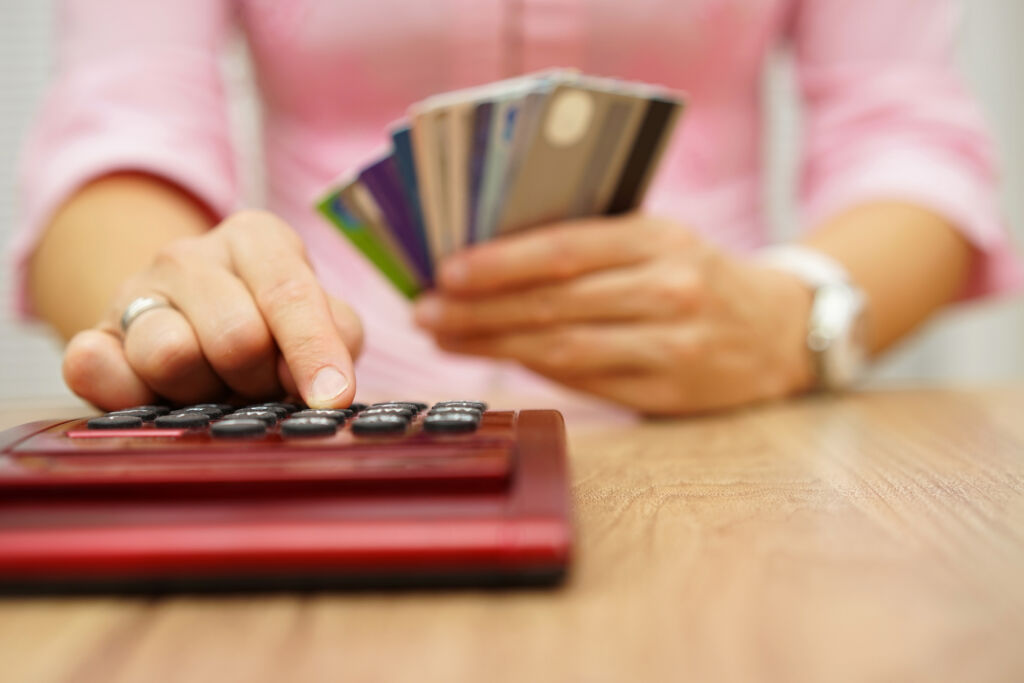 Woman Typing on Calculator with Credit Cards in Hand Woman Typing on Calculator with Credit Cards in Hand