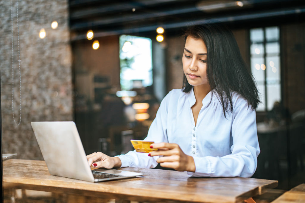 Woman with Laptop Looking Sad at Credit Card Woman with Laptop Looking Sad at Credit Card