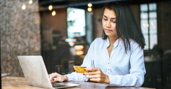 Woman with Laptop Looking Sad at Credit Card