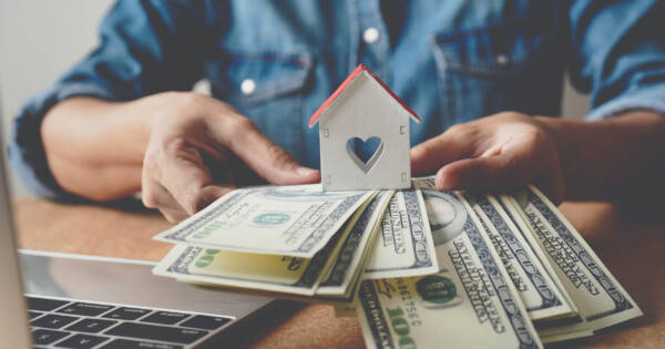 Man Holding Mini Home & Money