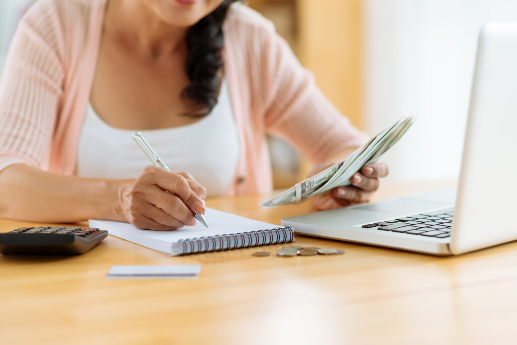Woman Recording Cash Spent on Notepad Woman Recording Cash Spent on Notepad