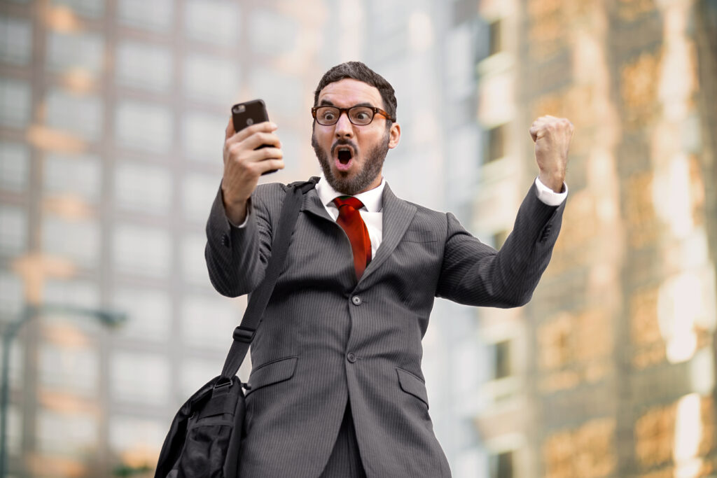 Investor Celebrating Looking at Mobile Phone Investor Celebrating Looking at Mobile Phone