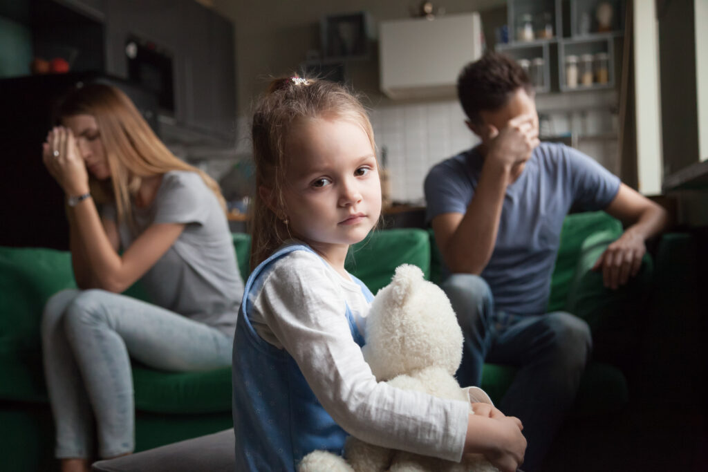 Child Sad with Parents Fighting in Background Child Sad with Parents Fighting in Background