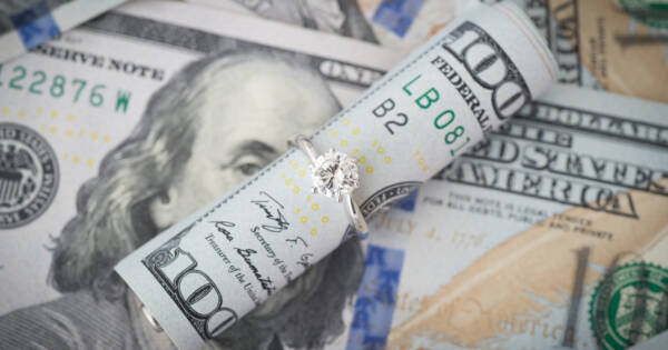 Wedding Ring Around Rolled Up $100 Dollar Bill